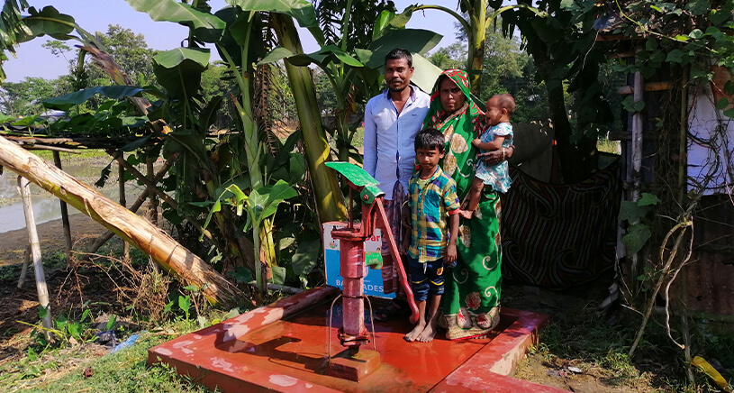 A man and his family marvel at a water pump